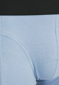  Lichtblauwe ondergoed met een gladde textuur en zachte stof. Kenmerkt zich door een zwarte tailleband en verstevigde stiksels langs de randen.