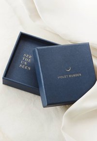 Marineblaues Geschenkset mit strukturierter Oberfläche, innen mit goldener Schrift "SEE THE UNSEEN" und "VIOLET HAMDEN" auf dem Deckel.