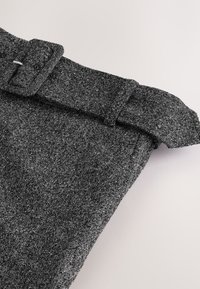 Højttaljede, kulgrå uldbukser i fiskebensmønster med et matchende bælte i samme stof og en rektangulær spænde.