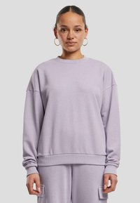 Sweatshirt viola chiaro con scollo rotondo, spalle scese e polsini a coste. Tessuto morbido e strutturato con vestibilità rilassata.