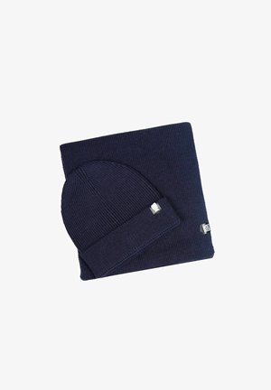 Navy-Blau gestrickte Mütze mit umgeschlagenem Saum, kombiniert mit einem passenden rechteckigen Schal. Beide weisen eine weiche Textur und subtile Nähdetails auf.