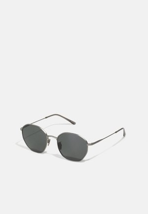 Ochelari de soare din metal cu lentile de culoare gri închis, formă octagonală a lentilelor, rame subțiri din metal și temple slabe. Design minimalist fără logo-uri vizibile.