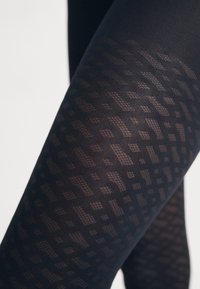 Tightly ajustadas con un diseño geométrico texturizado, estas medias negras con patrón presentan una apariencia semitranslúcida. El material es suave y se adapta al cuerpo.