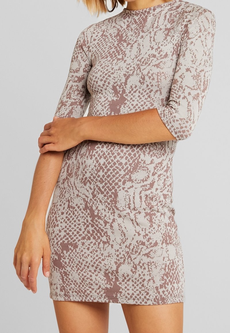 Lyhythihainen, sovitettu mekko vaaleanbeigellä pohjalla, jossa on vaaleanpunainen käärmeennahkakuosi. Pehmeä, joustava kangas, jossa korkea pääntie ja helma, joka on yli reiden puolivälin.