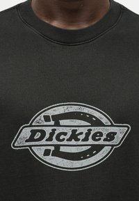 Μαύρο T-shirt με στρογγυλή λαιμόκοψη και φθαρμένο λευκό λογότυπο "Dickies" στο κέντρο του στήθους.