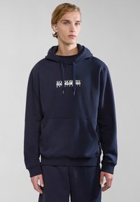 Sudadera azul marino de tejido suave, que cuenta con un bolsillo frontal y capucha concordón. Presenta un logo gráfico blanco en el área del pecho.