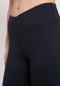Leggings neri a vita alta realizzati in un tessuto elastico e liscio, con un design senza cuciture e cuciture piatte per comfort e durata.