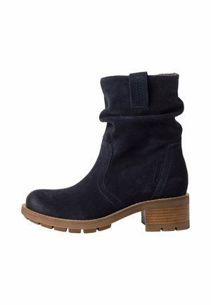 Navyblaue Wildleder-Stiefeletten mit einem schlaffen Design, ausgestattet mit einem gestapelten Holzabsatz und einer strukturierten Gummisohle für besseren Halt.