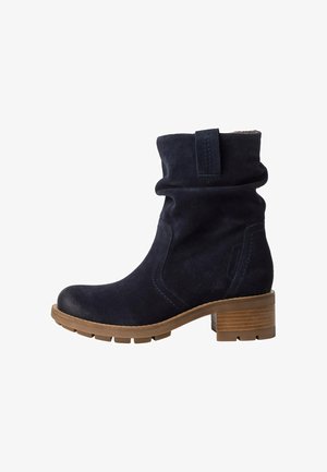 Stivaletti alla caviglia in suede blu navy con un design morbido, dotati di un tacco in legno impilato e una suola in gomma testurizzata per una buona aderenza.