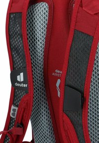 Mochila roja con tejido de malla transpirable con un patrón de diamante, correas reforzadas y un parche de logo en el lateral.