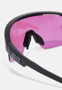 Lunettes de sport noires avec de grandes lentilles roses, dotées d'une monture robuste et de coussinets en caoutchouc pour le confort et la stabilité. Logo de la marque visible.