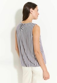 Blouse sans manches en rayures noires et blanches, en tissu léger, avec un détail froncé au niveau de l'encolure arrière.