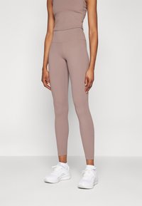 Strak aansluitende, hoge taille legging in een gedempt taupe kleur, gemaakt van rekbaar materiaal met een soepele textuur en minimale details.