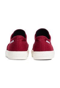 Rote Canvas-Sneaker mit niedrigem Schnitt, weißen Gummisohlen und kontrastierender schwarzer Innenauskleidung. Mit einem Logo-Tag an der Seite.