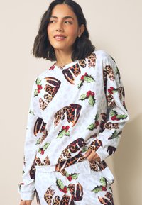 Wit shirt met lange mouwen, bedrukt met een speels dessin van luipaardvlekken, kerstklokjes en hulstbladeren. Zachte stof met een relaxte pasvorm.