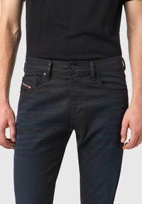 Mörkblå denimjeans med slim fit, med subtila blekningseffekter, fem fickor och en märkesetikett på framsidan av fickan.