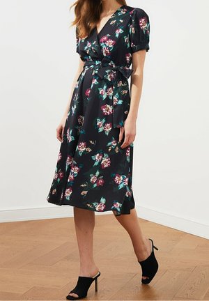 Robe portefeuille noire à fleurs avec des manches bouffantes courtes, une taille cintrée ornée d'un nœud et une jupe midi fluide. Le tissu semble léger.