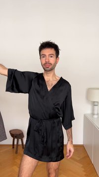 Black satin robe with a wrap design and wide sleeves, featuring a tie belt. The fabric has a smooth, shiny texture.