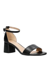 Sandales à talons blocs en cuir noir avec une bride de cheville et un design ouvert à l'avant. Texture lisse avec une esthétique simple et minimaliste.