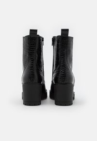 Bottines noires en cuir embossé crocodile. Bout carré, talon épais et fermeture éclair à l'arrière. Finition de surface texturée et brillante.