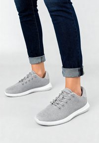 Graue Sportschuhe mit einer strukturierten Mesh-Oberfläche und weißer Gummisohle. Verfügen über runde Schnürsenkel und einen gepolsterten Kragen für Komfort.