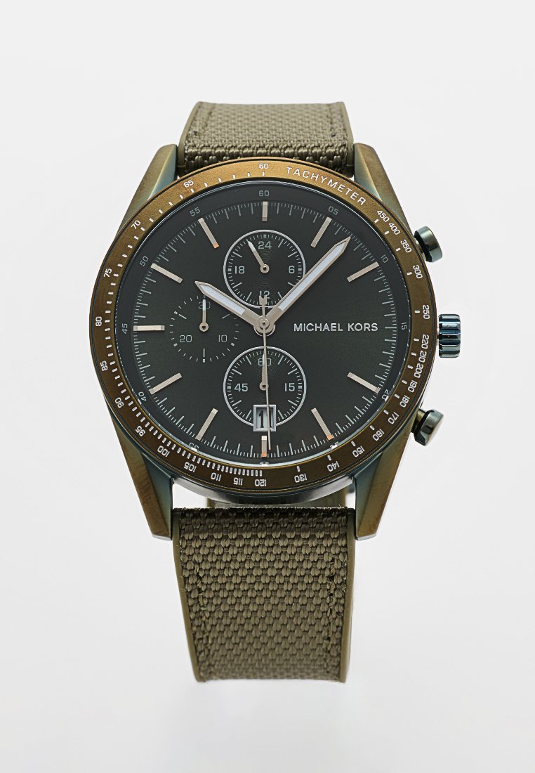 Reloj Michael Kors con esfera negra, tres subesferas, bisel tacómetro, agujas plateadas y correa de tela verde oliva con textura.