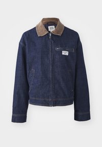 Jeansjakke i mørkeblått med kordfløyelskrage, frontlukking med glidelås, brystlomme og sidelommer; har kontrasterende gul søm.