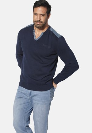 Navy sweater with a v-neck, featuring light denim shoulder accents and button details. Soft texture with ribbed cuffs and hem.