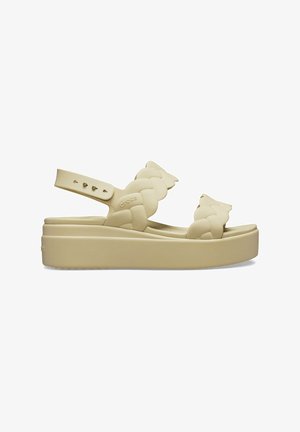 Beige platform sandaler lavet af blødt materiale, med flettede stropper og en justerbar ankelrem for en sikker pasform.