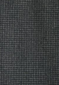 Tissu gris foncé avec un motif pied-de-poule subtil, présentant une texture fine et un design tissé, mettant en avant une apparence structurée en grille.