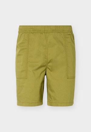 Olivo zelene kratke hlače srednje dolžine z elastičnim pasom in vidnim šivom spredaj na enobarvnem ozadju.