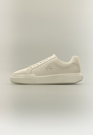 Minimalistisk off-white Calvin Klein sneaker med ruskindsoverdel, snøredesign og tyk gummisål vist fra siden på en neutral baggrund.