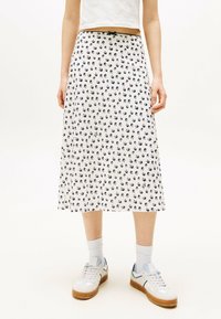 Gonna midi bianca con stampa di uccelli blu navy, caratterizzata da un cinturino aderente e un tessuto leggero, abbinata a scarpe da ginnastica bianche e calzini a coste.