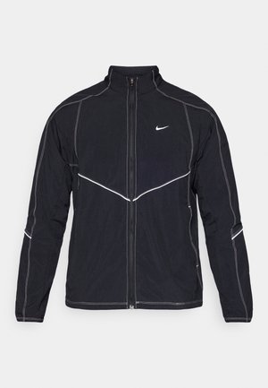 Casaco preto da Nike com gola alta, fecho de correr frontal e detalhes em costura branca. Apresenta mangas compridas e silhueta ajustada.