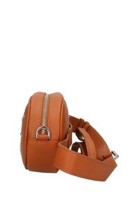 Ronde, oranje neplederen tas met zilveren rits, verstelbare schouderband en decoratieve studs aan de zijkant. Vloeiende textuur en compacte vorm.