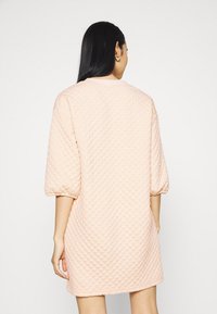 Gestepptes pinkes Kleid mit lockerer Passform, überschnittenen Schultern und rundem Ausschnitt. Es hat ein Rautenmuster und einen schlichten Saum.