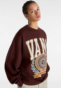 Brun sweatshirt med oversized passform som har stor "VANS"-text, atletisk logotyp och design av grön löv på framsidan. Mjuk tyg.