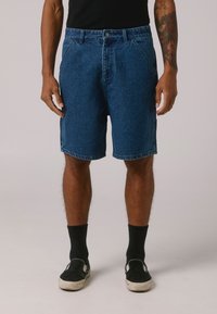 Pantalones cortos de mezclilla, lavado azul, que presentan un clásico diseño de cinco bolsillos, corte recto, costuras visibles y una cintura con cierre de botón.