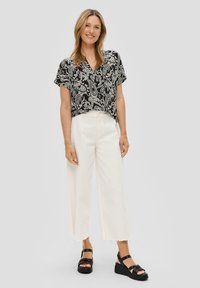 Zwart-wit paisley-patroon korte mouwen top, witte wijde broek en zwarte platform sandalen. Gestructureerde stof met een ontspannen pasvorm.