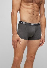 Dunkelgraue Boxershorts mit einem schwarzen elastischen Bund, auf dem das Wort "BOSS" in Weiß steht. Hergestellt aus weichem, dehnbarem Material.