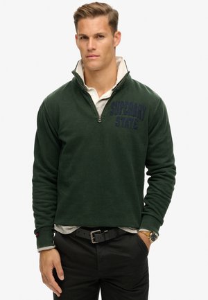 Pullover verde con zip a quarti realizzato in morbido tessuto, dotato di un colletto chiaro a contrasto e del logo blu scuro "SUPERDRY STATE" sul petto.