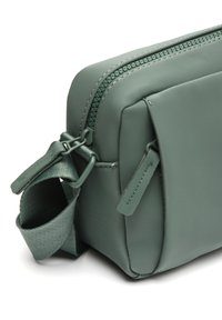 Borsa in materiale sintetico verde con finitura texturizzata, dotata di chiusura con zip e manico in tessuto. Include un piccolo dettaglio sulla cerniera.