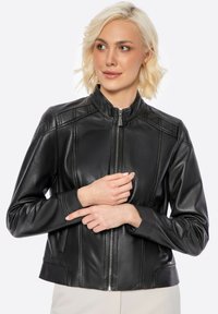 Black leather jacket with a stand collar, zip closure, and fitted design. Features side pockets and decorative stitching details.