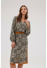 Czarna i beżowa sukienka w wzory z długimi rękawami, dekoltem w kształcie litery V, marszczoną talią i kontrastowym brązowym wykończeniem, charakteryzująca się teksturowanym materiałem i płynną sylwetką.
