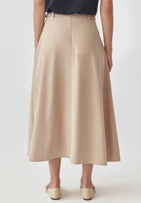 Beige midi-rok met een gladde textuur, voorzien van een tailleband, A-lijn vorm en een enkel-lange zoom. De stof is lichtgewicht en valt soepel.