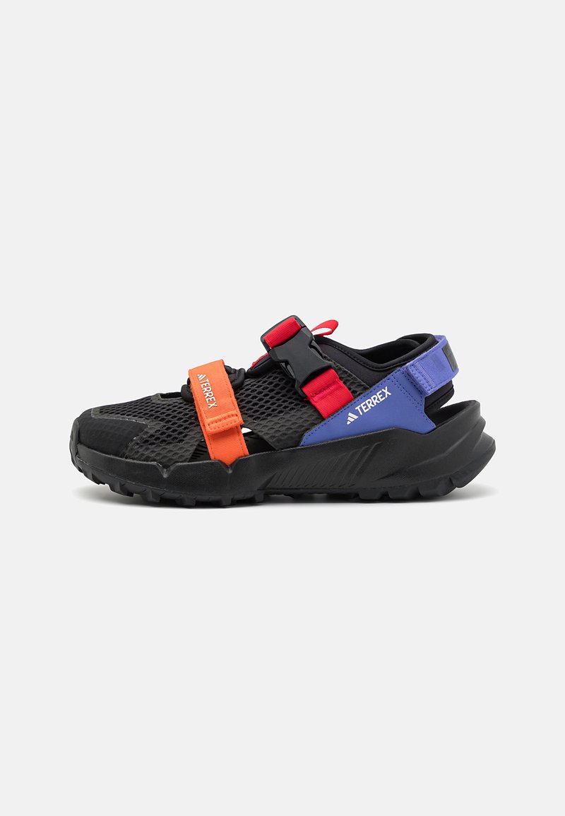 Sorte atletiske sandaler med mesh-overdel, oransje og røde stropper, og lilla accenter. Har en robust svart såle for grep.