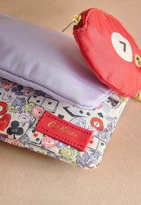 Viacerozdielové púzdro z fialovej a červenej látky s kvetinovými vzormi, zlatým zipsom a červenou značkovou nálepkou s nápisom "Cath Kidston".