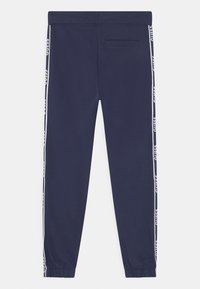 Marineblauwe joggingbroek van zachte stof, met witte logo-strepen langs de zijkanten en een elastische tailleband met omgeslagen enkelmanchetten.