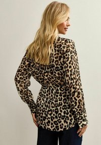 Blusa de estampado de leopardo con tejido ligero y transparente, mangas largas, cintura ajustada y puños con botones.