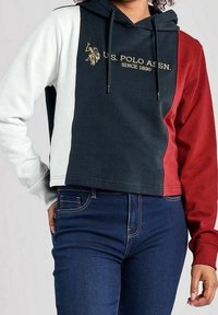 Kort hoodie med marinblå, röd och vit paneler; har en guldig U.S. Polo Assn. logotyp; texturerat tyg, justerbar dragsko på huvan.